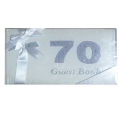White guest book wrapped with a white satin ribbon on the left; pale blue embossed '70' and 'Guest Book' on the cover.