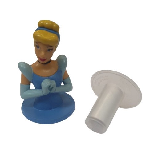 Blue-dressed toy princess figurine sitting on a round base with hands clasped, plus a separate white plastic stopper-like piece nearby