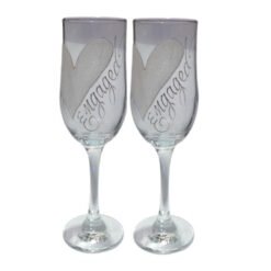 Two champagne flutes with silver heart designs and the word 'Engagement' scripted along the glass on a white background.