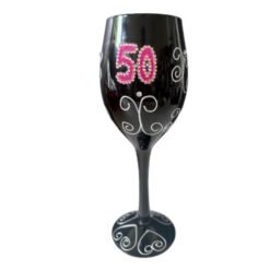 Black wine glass decorated with pink rhinestone '50' and white swirls, celebrating a 50th birthday.