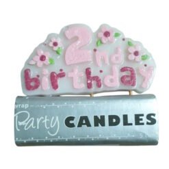Pink and white '2nd birthday' cake topper with flower accents resting on a blue 'Party Candles' package.