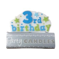 Fondant cake topper reading '3rd birthday' in blue and green with stars, resting on a gray 'Party Candles' package.